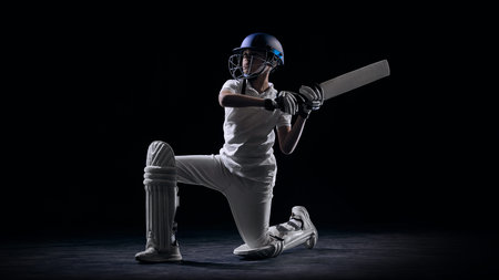 Junior cricket player playing attacking shot on dark background. Concept of dynamic sports action, youth cricket development, competitive match moment and athletic advertising design.の写真素材