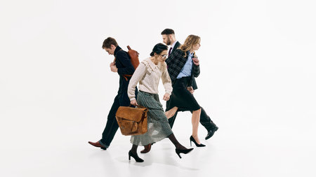 Four professionals walking in synchronized formation against white background. Concept of teamwork synergy, corporate culture and modern business fashion campaign with dynamic energy.の写真素材