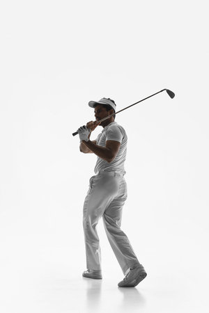 Golfer holding club at top of backswing on white background. Concept of controlled swing mechanics,...