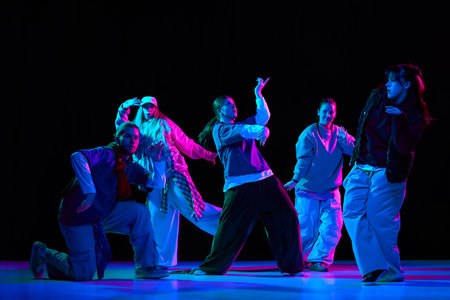 Hip hop dance crew performing choreography with neon lighting on stage for music promotion,...