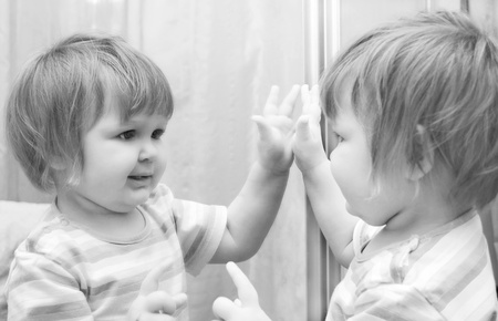 A girl looks in the mirror. Black and White image of baby.の写真素材