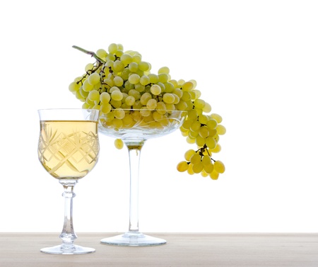 Wine in a glass with grapes, isolated on a white background.