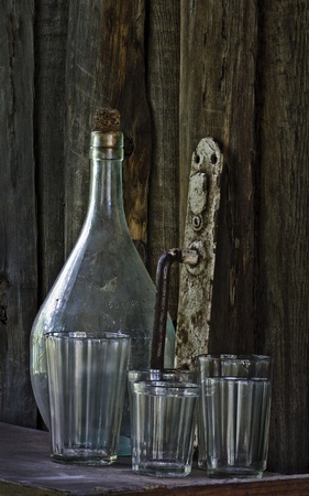 Still life - old bottle, glass, doorhandle, balance on wooden background の写真素材