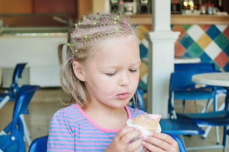 little girl eating ice cream in a cafeの写真素材