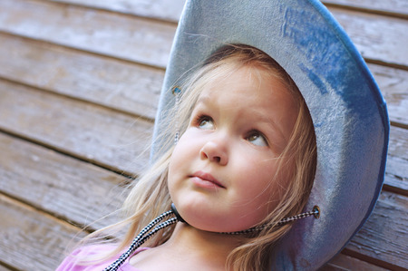 Happy little girl posing on wooden backgroundの写真素材