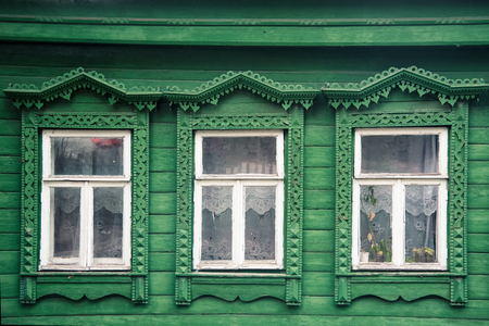 Green facade of the old Russian village wooden house with carved ornaments elementsの写真素材
