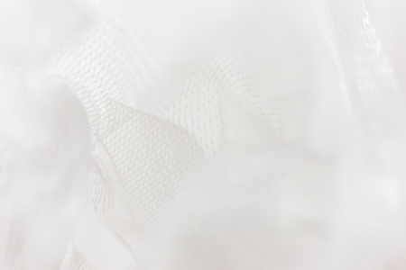 Mesh fabric, tulle  background texture. close-up of a soft white mesh fabric. selective focus with blurred background.の写真素材