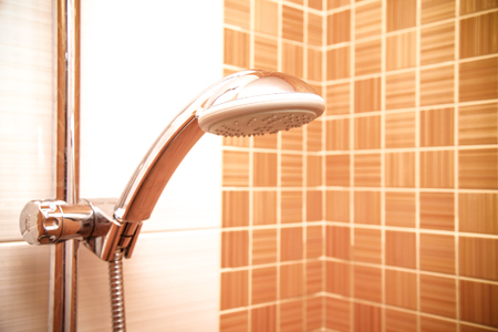 closeup of a height-adjustable shower head  in modern bathroom with orange wallの写真素材