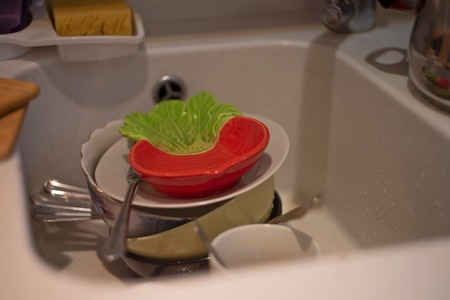 A lot of dirty dishes in the white sink in the kitchenの写真素材
