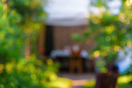 Blurred summer garden background and house in the rays of the bright sun. Bokeh, green bushes and sun highlightsの写真素材