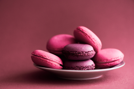 Assorted French Macarons. Multi-coloured macaroons cookies for dessert. Macaroons on colored background. Pink and purple french cookies macarons on red background. Gift for Valentine's Day. Selrctive focusの写真素材