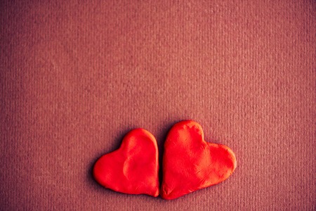 Two red  hearts made from modeling clay against a purple paper background. The concept of Valentine's Day February 14. Loved together.の写真素材