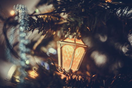 Christmas atmospheric background. A close-up fragment of a Christmas tree with toys, lights of Gerland and tinsel. Retro toning style, selective soft focus.の写真素材