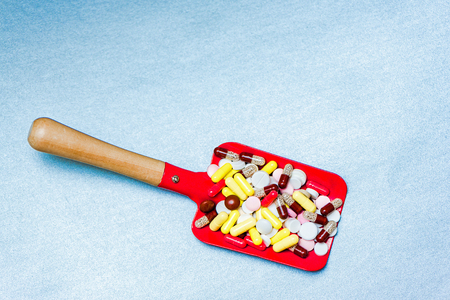 Toy baby scoop full of multi-colored pharmaceutical pills and capsules. Pills, drugs  pharmacy, medicine or medical on blue background. Healthycare concept, selective soft focus.の写真素材