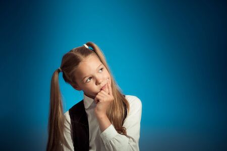 Cute Caucasian schoolgirl thought about the task, putting a hand to her face, looking to the side