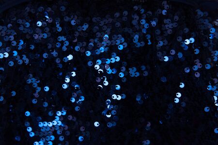 Background sequin. Holiday abstract glitter background with blue blinking lights. Fashion fabric sequins in bright colors.の写真素材