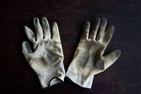 A old dirty textile work gloves on dark wooden background