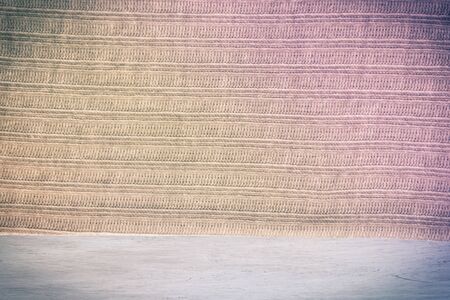 Knitted beige soft fabric on a light painted wooden board. Background, blank for design. Original...