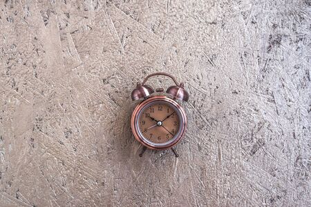 Clock at 10 O clock in the morning with vintage style alarm clock golden wooden background. Windup...