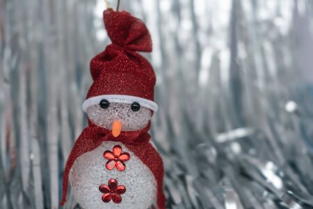 Christmas Decoration snowman on shiny silver christmas paper close up. Art Christmas Greeting Card. Christmas, winter concept. Soft selective focus.の写真素材
