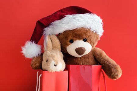 Christmas card with Teddy Bear and banny With a gift and holiday decoration. Hare and bear in red gift bags.の写真素材