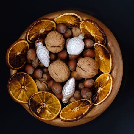on black table, top view, flat lay. Festive table settin. Wooden bowl with nuts, walnuts and...