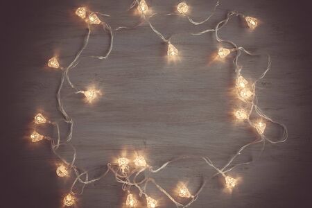 Light bulb on wooden background.  Space for your task or message. Glowing Christmas garland frame on...