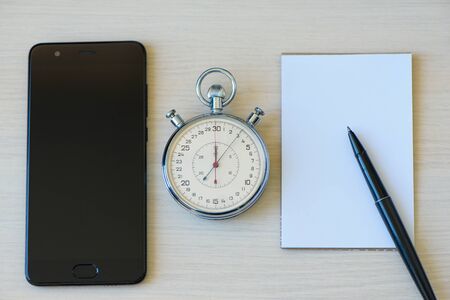 Smartphone, Notepad, pen And Stopwatch biege desk table background. The concept of time managementの写真素材