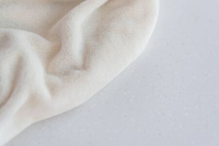 Soft cozy plush fabric with pile lies in beautiful folds on white marble countertop background. Copy space. Delicate mock up flat lay.の写真素材