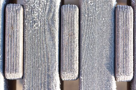 Background of part a wooden bench surface covered with hoarfrost, frost, morning sunlight. Rime....