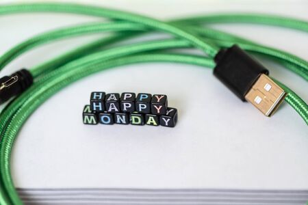 Happy Monday of blocks on white page open notebook on desktop and green usb wireの写真素材