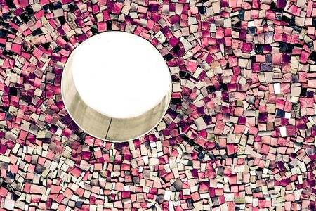 Mosaic on the wall with fragments of purple, pink, lilac, white, black colors with small round frame. Abstract colorful backgrounds retro vintage toned.の写真素材