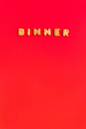 The Letter Word Dinner. Alphabet Cookie Cracker on red background paper texture. Red empty backgrounds. Top view, copy space, flat lay.の写真素材