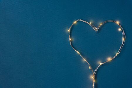 Heart laid out of a luminous garland on a blue background. The concept of hot love. Valentine's Day blank for congratulationsの写真素材