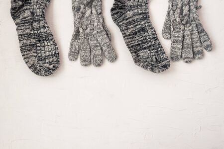Warm female gray knitted gloves, socks of border on white textured background. Flat lay, top view minimal winter fashion concept.の写真素材
