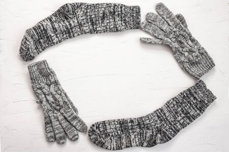 Warm female gray knitted gloves, socks of round frame on white textured background. Flat lay, top view minimal winter fashion concept.の写真素材
