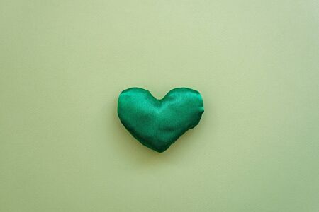 Lovely green handmade fabric heart shaped on textured paper background. Creativity object,...