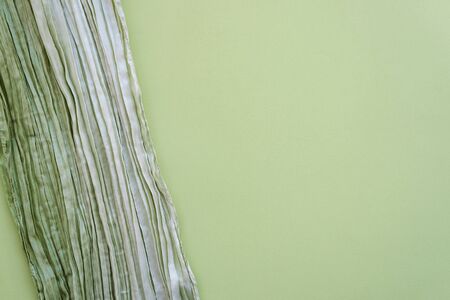 The texture of the background picture the olive and sage green corrugated fabric with parallel or diagonal folds on textured paper. Blank for design, concept of nature, springtime, fresh greenery.の写真素材