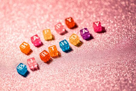 Happy Birthday with colored blocks letters on pink glitter backgrounds. Greeting card to celebrate.の写真素材