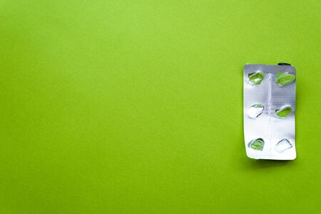 Empty pill blister pack on a green background. Drug prescription for treatment medication....