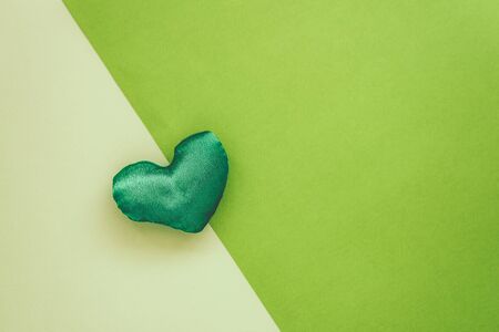 Lovely green handmade fabric heart shaped on textured paper background.の写真素材