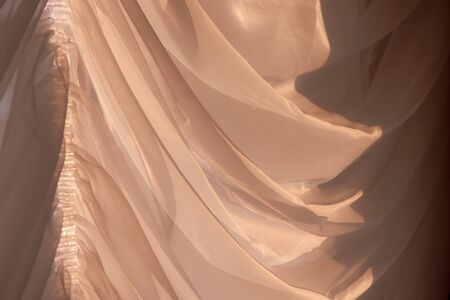 Elegant, thin transparent curtain on the window, by sunlight. Vintage toned photo. Selective soft focus.の写真素材