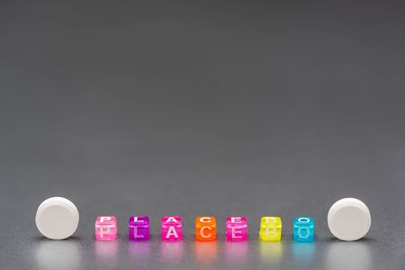 Placebo pill. White Pills and word placebo on silver grey background. Placebo effect, fake medical treatment, minimal creative concept. Copy spaseの写真素材