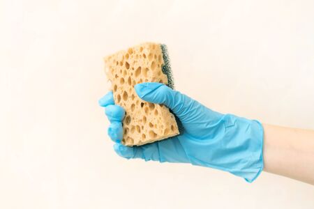 Blue cleaning gloves with a yellow sponge against a white background. cleaning service conceptの写真素材