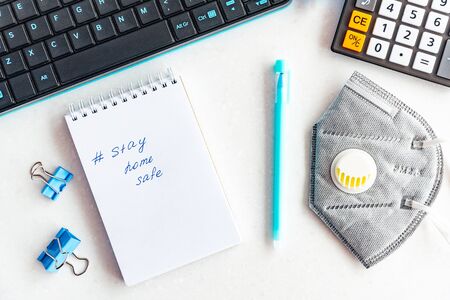 Words stay at home written on notepad, concept of self quarantine at home as preventative measure against virus outbreak. Flat lay, keyboard, note books, staying at home during emergencyの写真素材