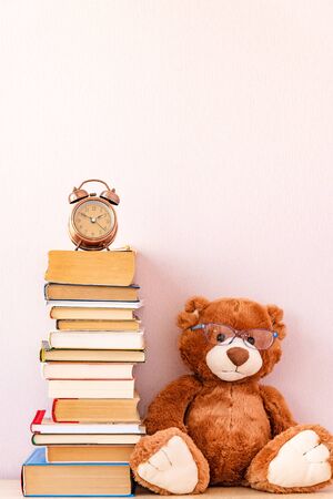 Soft Stuffed toy Teddy bear with glasses, a stack of books and alarm clock. Education concept, back to school, reading speedの写真素材