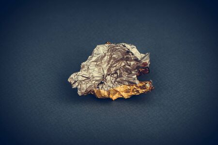 candy golden wrapper foil empty and open on dark blue background with copy space for your textの写真素材