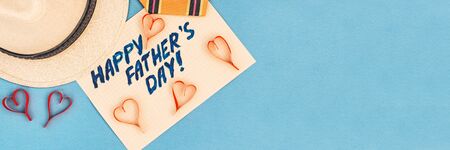 Happy Father's Day inscription with tie, hat handmade hearts on blue background. Greetings and presentsの写真素材
