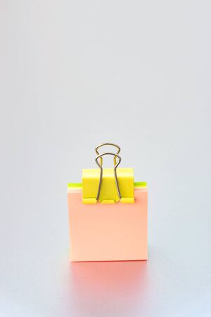 Yellow paper clip on clean color paper blok - a cover on a silver grey background with a small letter for inscriptionの写真素材