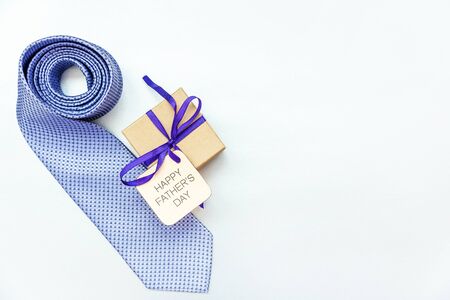 Happy Father's Day inscription with tie and gift box on white background. Greetings and presents